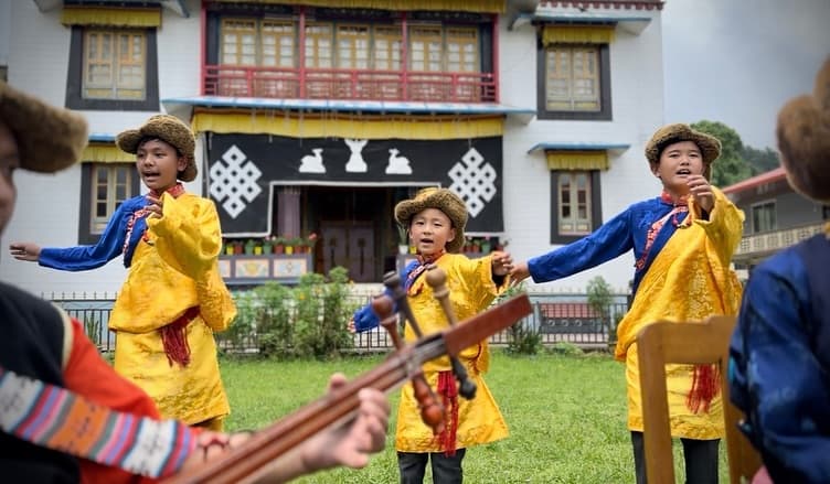 Young performers of Gangjong Doeghar in traditional costume performing in front of a Tibetan monastery in Kalimpong, India